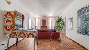 A spacious room with a wooden herringbone floor, a red sofa, a small potted plant, and a colorful wall decoration. - Giudici Three Bedrooms Apartment by Wonderful Italy (Palermo)