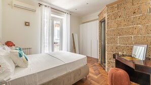 A bedroom with a bed, a wooden desk, a mirror, and a brick wall. - Giudici Three Bedrooms Apartment by Wonderful Italy (Palermo)