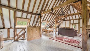 Un intérieur rustique avec des poutres apparentes, un coin repas et un canapé.