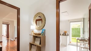 A hallway with a wooden floor, a mirror, and a shelf with papers and a basket. - Ground Floor Apartment with Garden 'Costa Quebrada' (Liencres)