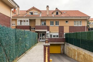 Un edificio residencial con techo de tejas rojas, fachada de ladrillo y puerta de garaje amarilla.
