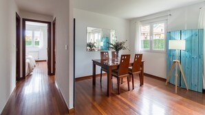 A dining area with a wooden table and chairs, a mirror, and a window with curtains. - Ground Floor Apartment with Garden 'Costa Quebrada' (Liencres)