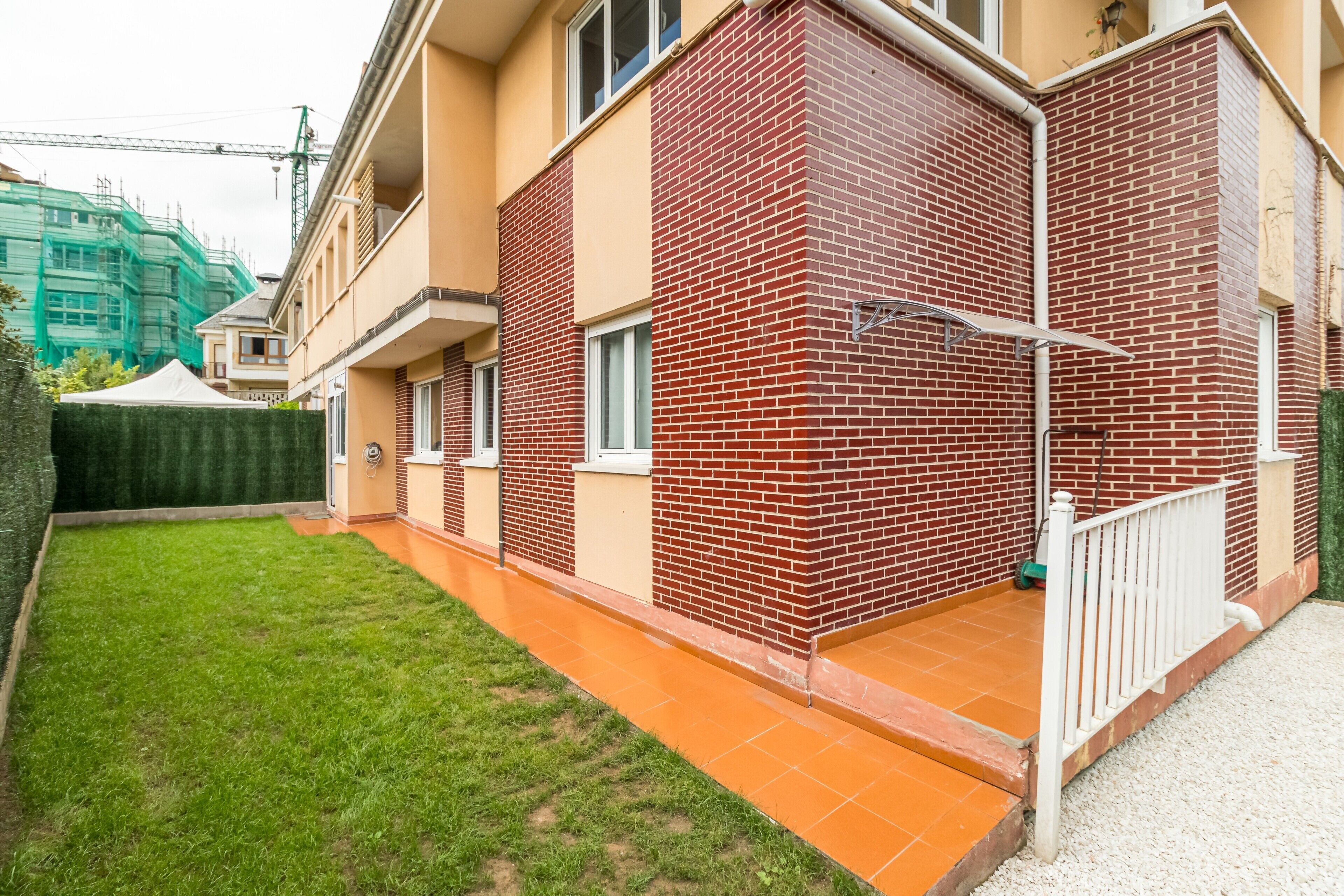Un immeuble résidentiel à la façade en briques, doté d’un petit balcon et d’une pelouse bien entretenue.