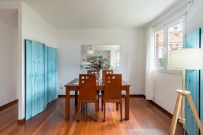 Un coin repas avec une table et des chaises en bois, un vase rempli de fleurs et une lampe.