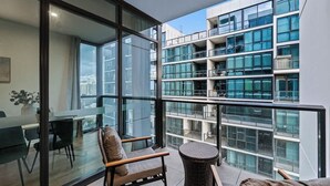Un apartamento moderno con ventanas amplias, zona de comedor y balcón con mobiliario de mimbre.