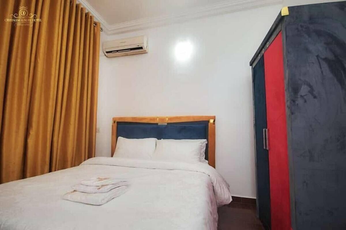 A hotel room with a bed, a wardrobe, and an air conditioning unit.