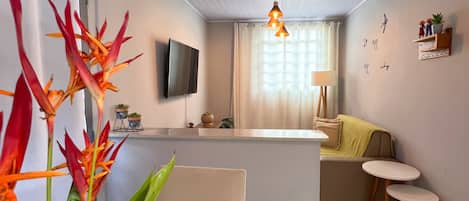 Una sala de estar moderna con un televisor de pantalla plana, una mesa de comedor y una zona de cocina con mostrador.