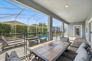 Uma área de varanda coberta com piscina, mobiliário de exterior e vista para a paisagem ao redor.