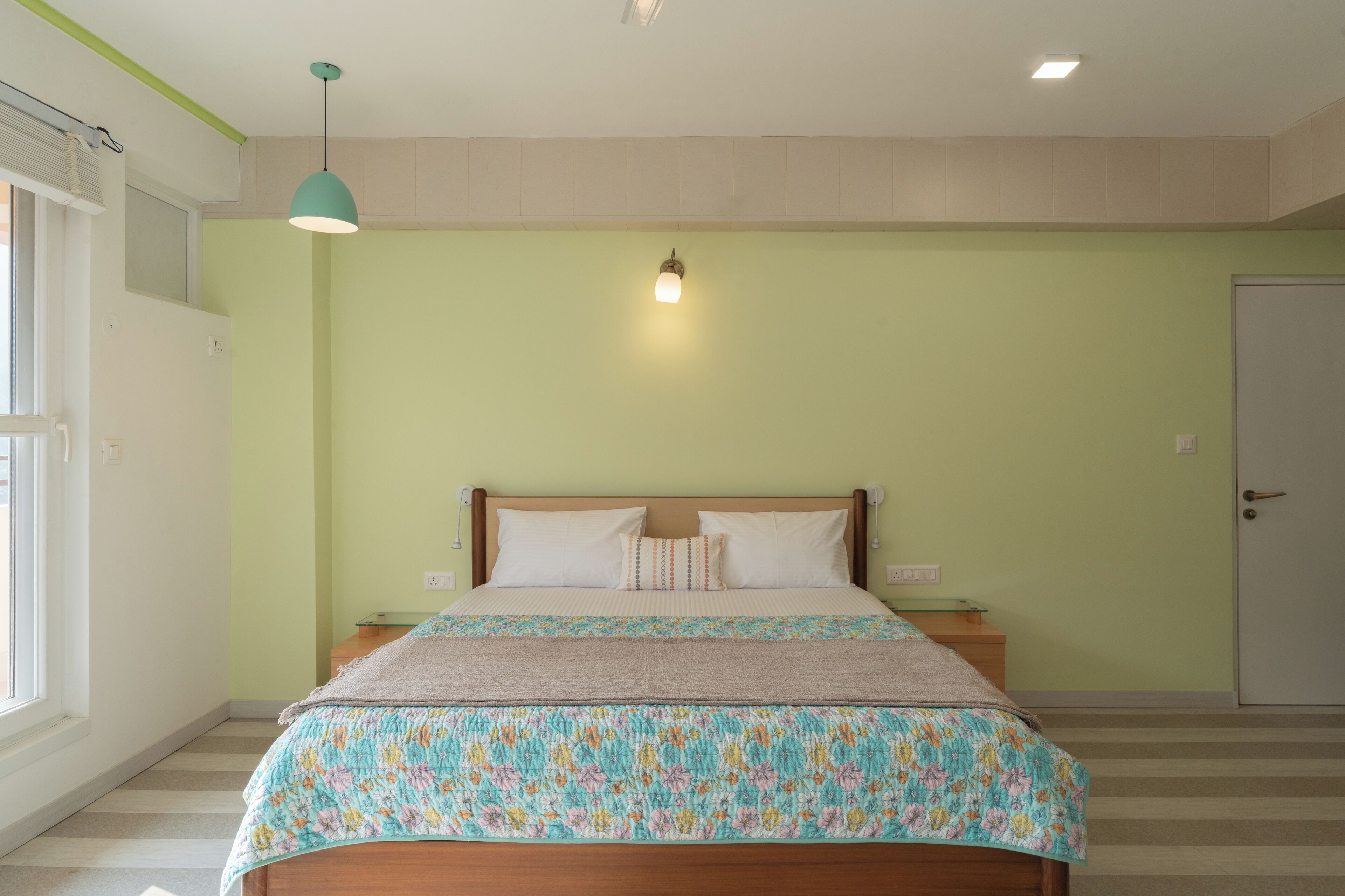Un dormitorio con cama, mesita de noche, lámpara y puerta.