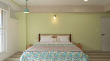 Een slaapkamer met een bed, nachtkastje, lamp en een deur.
