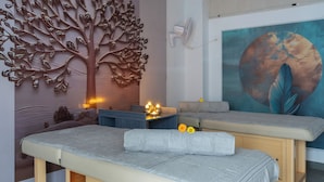 A massage therapy room with a large tree wall art, a painting, and a massage table. - Better Life Homes - For active seniors above 50 years (Solan)
