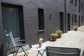 A modern building with a dark brick exterior, a wooden deck, and outdoor seating.