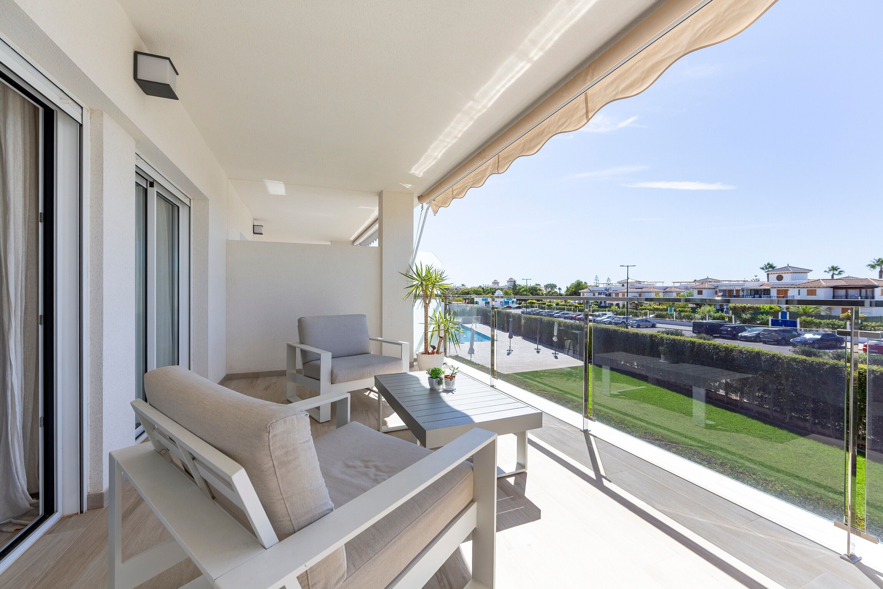 Een balkon met een bank, stoelen, een tafel en een bloempot.