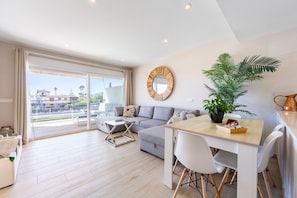 A modern living room with a sofa, a dining table, and a large window. - Magna Vera, new, bright and family-friendly accommodation. (Vera playa)