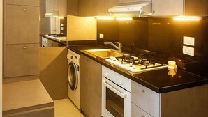 A modern kitchen with built-in appliances, a washing machine, and a stove.