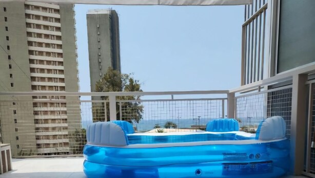 An inflatable pool on a tiled patio with a view of tall buildings in the background.