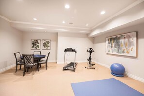 A room with a treadmill, exercise ball, and a dining table with chairs.