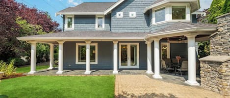 A two-story house with a covered patio and a stone wall.