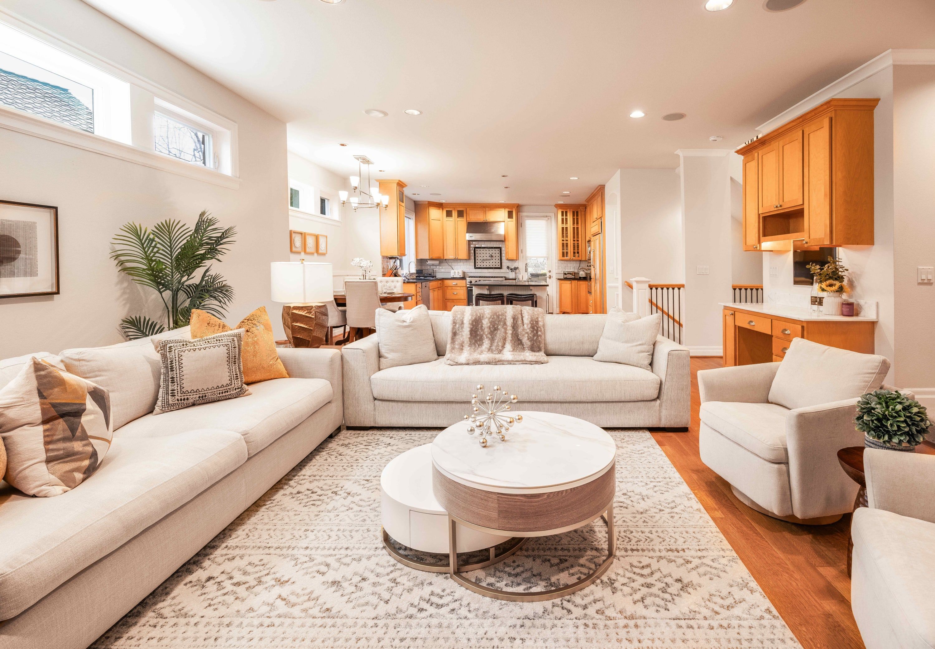 A spacious living room with a large L-shaped sofa, a round coffee table, and a kitchen in the background.