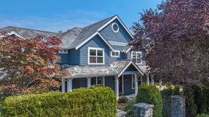 A two-story house with a gabled roof, a front porch, and a circular window on the second floor. - Grand Bellevue DT Villa 5,010 sqft, near BV Square (Bellevue)