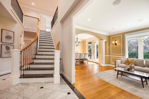 A spacious living area with a staircase, a dining area, and a sofa set.