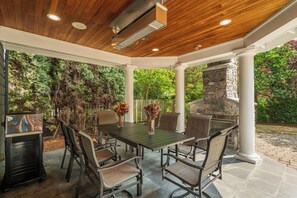 An outdoor patio with a stone fireplace, a dining table with chairs, and a grill. - Grand Bellevue DT Villa 5,010 sqft, near BV Square (Bellevue)