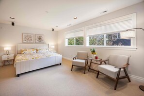 A bedroom with a bed, two chairs, a nightstand, and a window with blinds. - Grand Bellevue DT Villa 5,010 sqft, near BV Square (Bellevue)