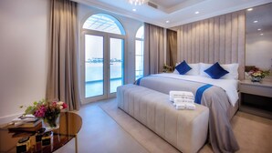 Un'ampia camera da letto con un letto grande, un comodino con un vaso di fiori e vista sul mare attraverso un'ampia finestra.