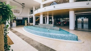 A spacious indoor pool area with a curved design, surrounded by multiple levels of balconies and a central staircase.