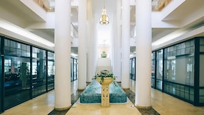 A spacious interior with high ceilings, a central staircase, and a decorative planter.