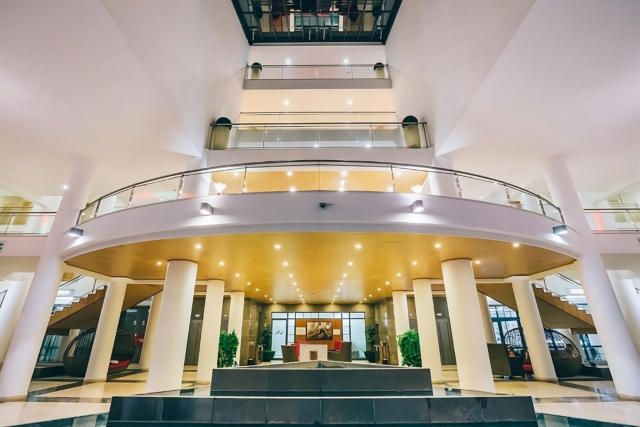 A multi-level atrium with a central open area, glass railings, and a staircase.