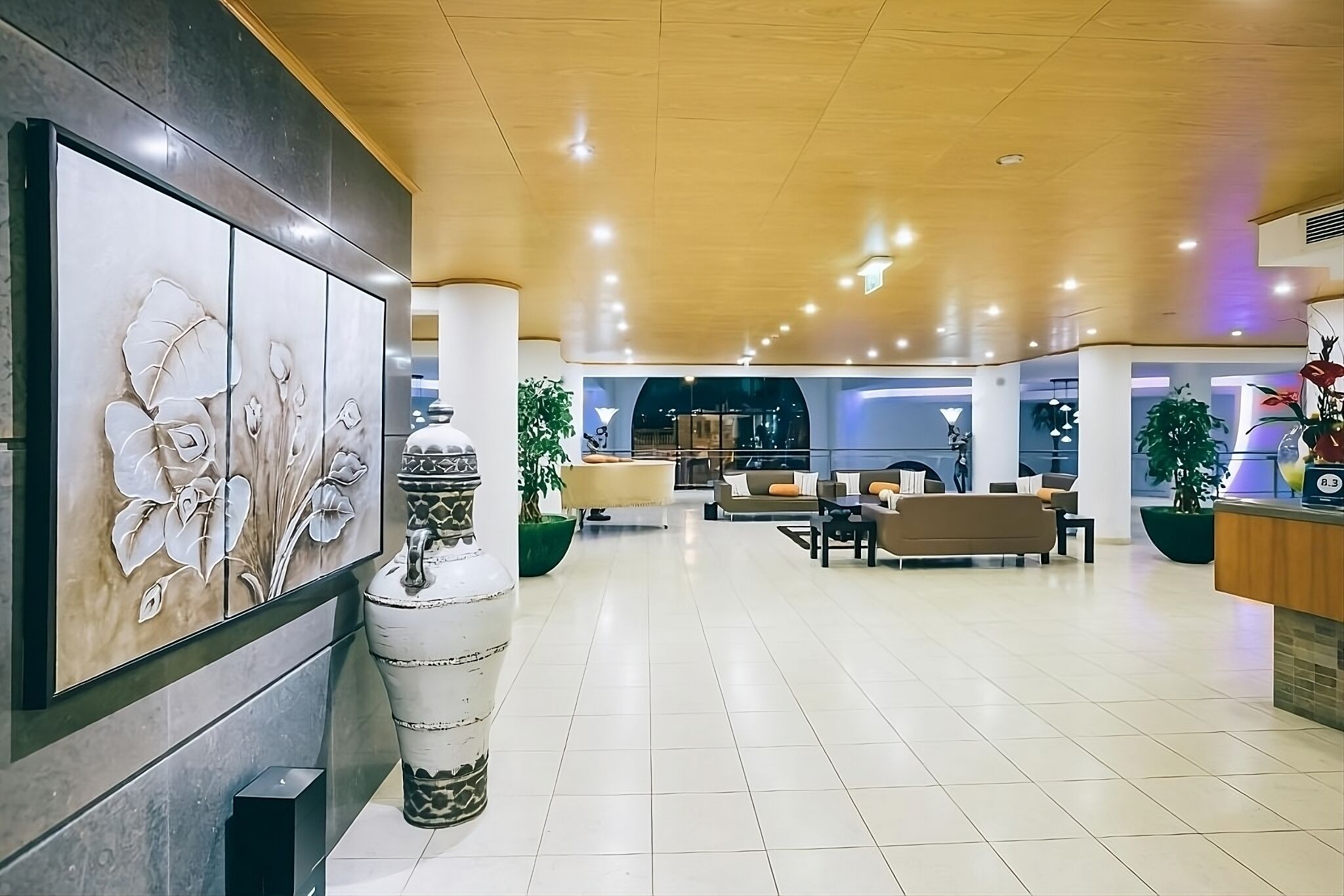 Un vestíbul ampli amb un disseny modern, que inclou una gran obra d'art floral abstracta, un vas decoratiu i una zona de recepció amb seients.