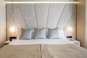 Une chambre à coucher moderne avec un grand lit, une tête de lit ornée d’un motif géométrique et des lampes de chevet.