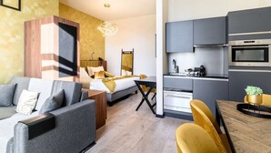 Une chambre d’hôtel moderne équipée d’un lit, d’un canapé, d’une table à manger et d’une kitchenette.