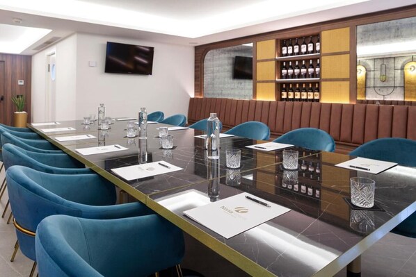 A conference room with a long table, blue chairs, and a wine display.