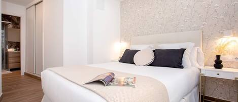 A bedroom with a bed, bedside tables, a nightstand, and a window.