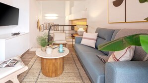 A modern living room with a sofa, coffee table, and a flat-screen TV mounted on the wall. - Luxury Apartment in Sevilla Center. Pajaritos V (Seville)