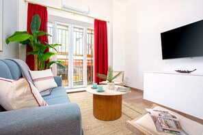 A modern living room with a blue sofa, a wooden coffee table, and a flat-screen TV mounted on the wall. - Luxury Apartment in Sevilla Center. Pajaritos V (Seville)