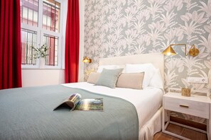 A neatly made bed with a magazine, a bedside lamp, and a nightstand with a lamp. - Luxury Apartment in Sevilla Center. Pajaritos V (Seville)