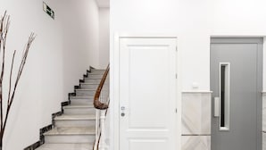 A staircase with a wooden handrail, a white door, and a grey door with a small window. - Modern Apartment in Prime Location. Marín García III (Málaga)