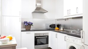 A modern kitchen with white cabinetry, a stainless steel range hood, a microwave, a dishwasher, and a washing machine. - Modern Apartment in Prime Location. Marín García III (Málaga)