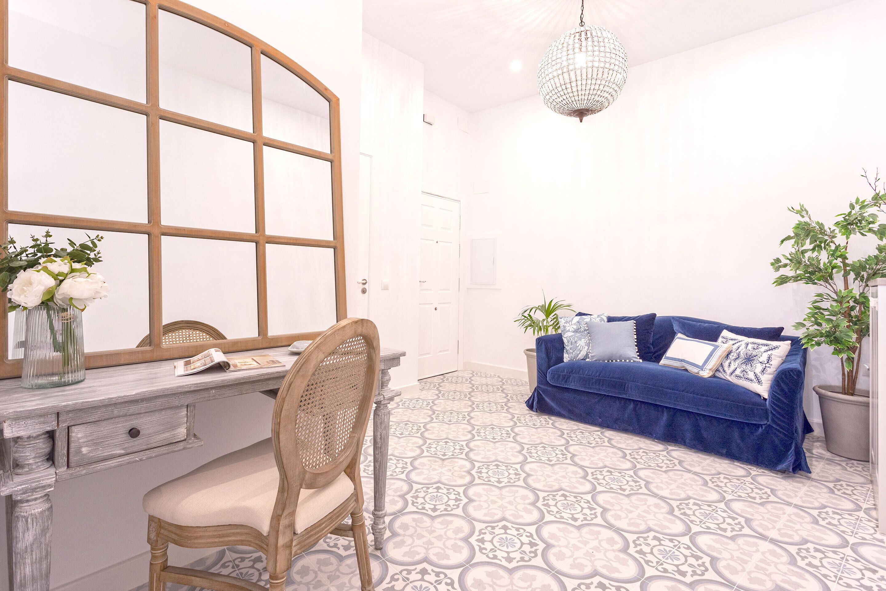 Ein Zimmer mit einem Holztisch, einem Stuhl, einem blauen Sofa und einer Topfpflanze.