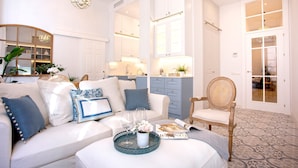 Un salón amplio con un sofá blanco, una silla de madera y una mesa de centro con una bandeja.
