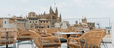A rooftop terrace with wicker furniture and a view of a historic building.