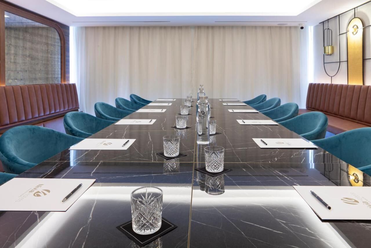 A conference room with a long table, blue chairs, and a marble table surface.