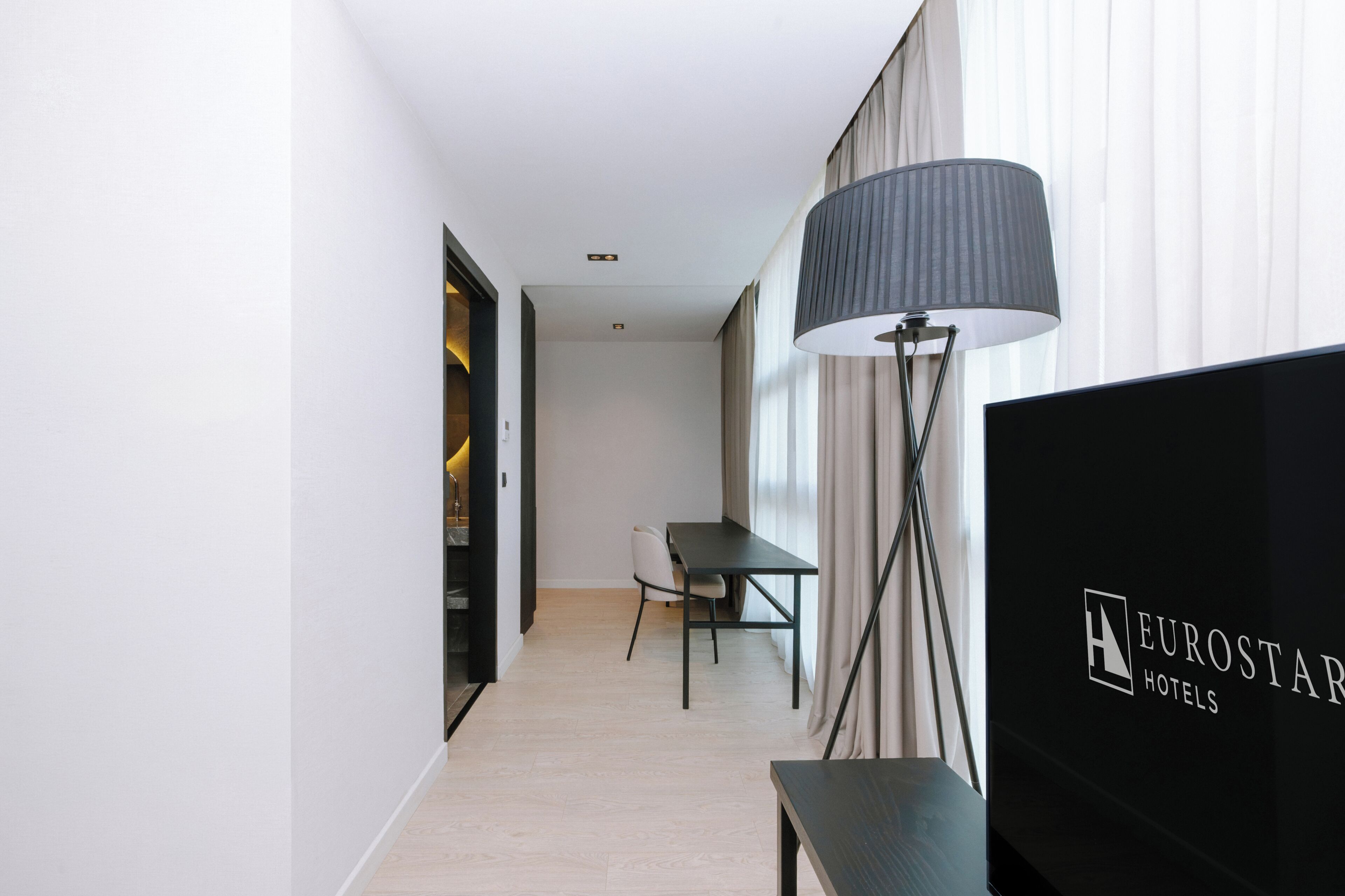 En hotelgang med et spiseområde, en lampe og et fjernsyn, der viser hotellets navn.