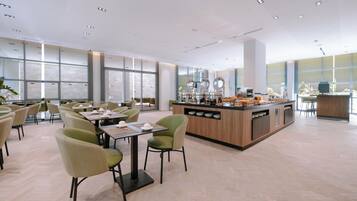 Un vaste espace dédié à la salle à manger, doté de hauts plafonds, de grandes fenêtres et d’un comptoir central avec un espace pour préparer le café.