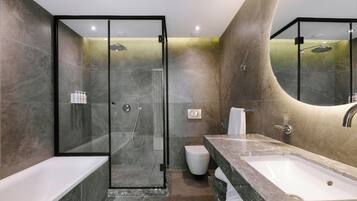 Un baño moderno con ducha envuelta en cristal, inodoro blanco y tocador de mármol con lavamanos.