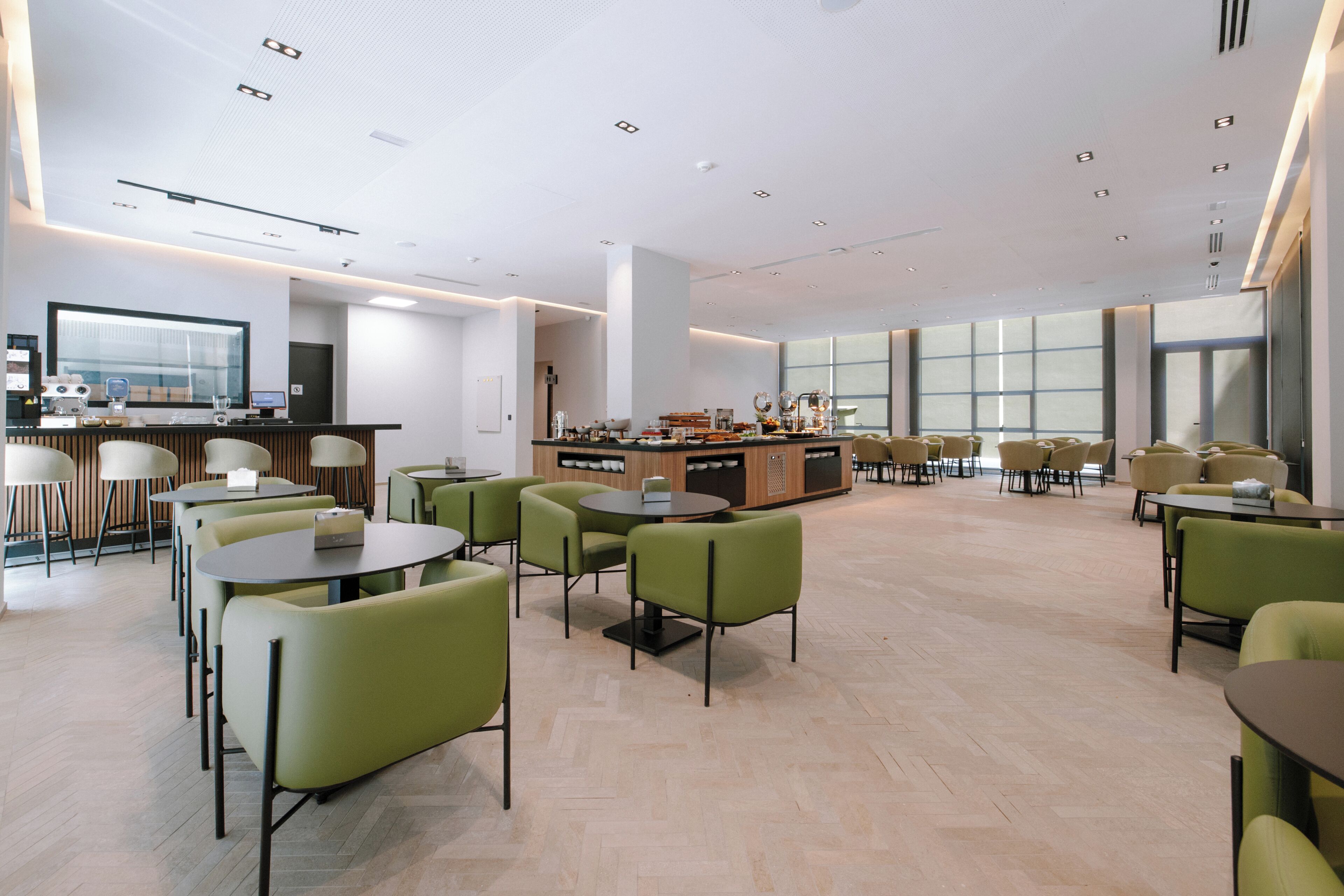 A spacious indoor area with multiple seating arrangements, a central counter, and large windows allowing natural light.