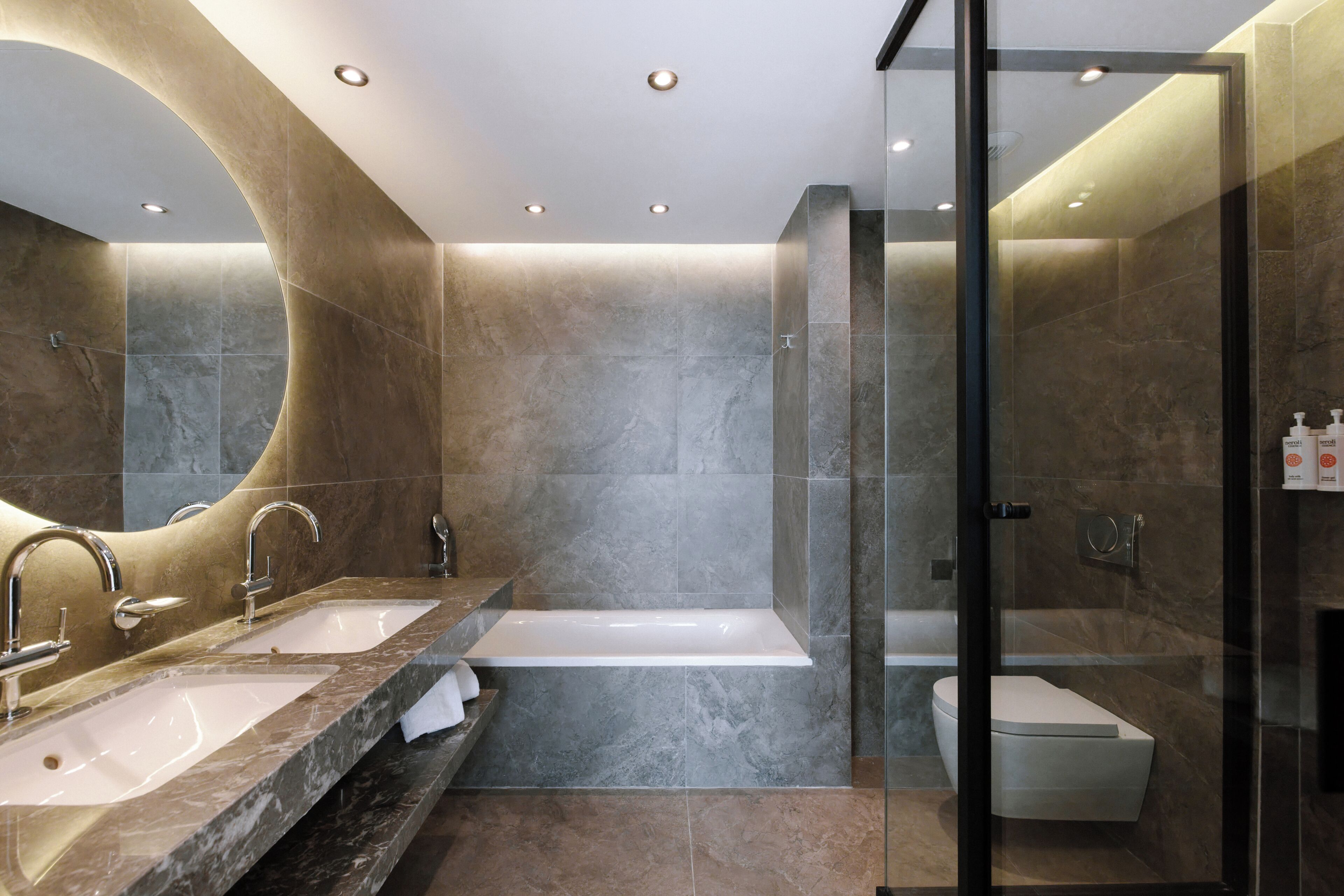 A modern bathroom with a glass-enclosed shower, a double sink vanity, and a separate toilet.